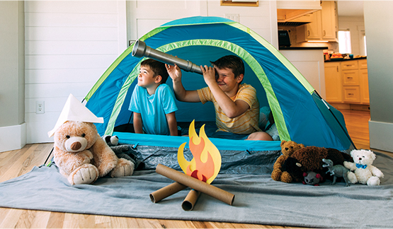 Two children acting out a camping trip from inside the home